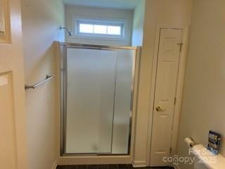 bathroom featuring toilet and a shower with door