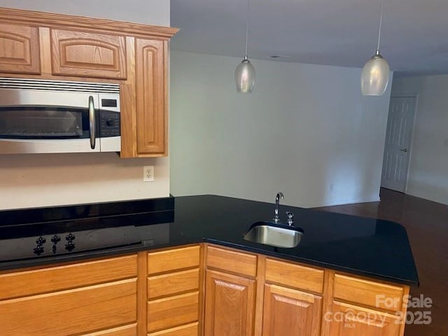 kitchen featuring hanging light fixtures, sink, light brown cabinets, and cooktop