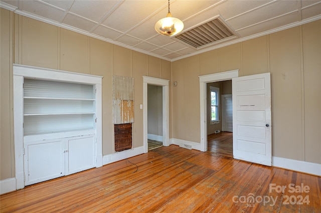 unfurnished bedroom featuring wood-type flooring and crown molding