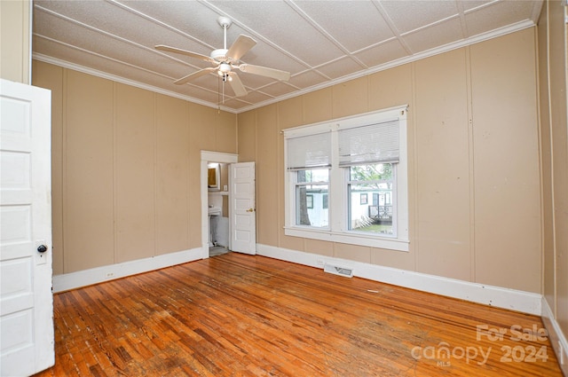 empty room featuring ceiling fan, hardwood / wood-style floors, and crown molding