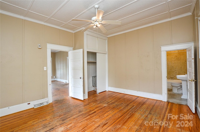 unfurnished bedroom featuring ornamental molding, wood-type flooring, ensuite bath, and ceiling fan