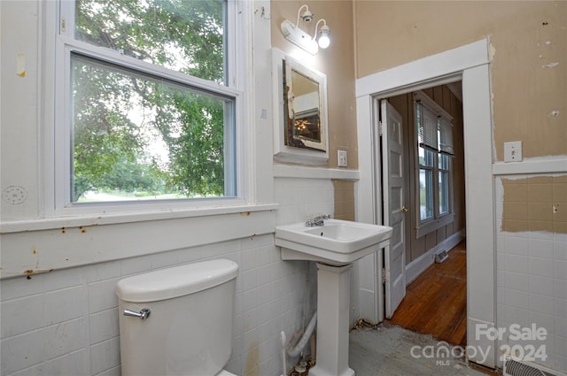 bathroom with wood-type flooring, tile walls, toilet, and sink