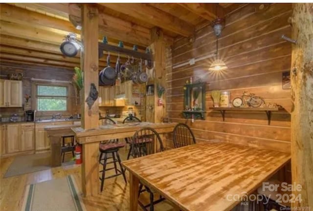 dining space with wooden walls, light hardwood / wood-style floors, and beamed ceiling