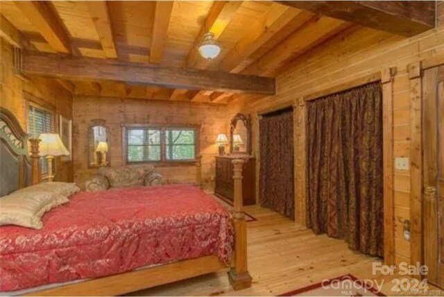 bedroom featuring wooden ceiling, beamed ceiling, wood walls, and light hardwood / wood-style flooring