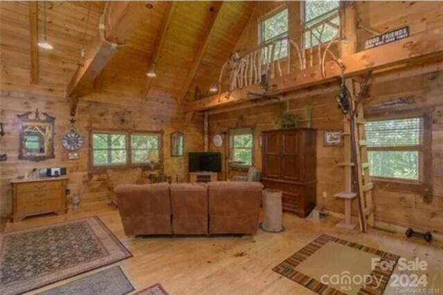 living room featuring beamed ceiling, light hardwood / wood-style flooring, wood walls, and wood ceiling