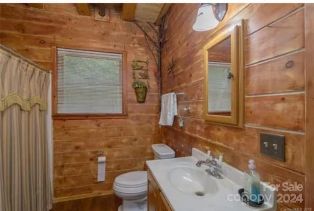 bathroom with a shower with shower curtain, wood walls, vanity, and toilet