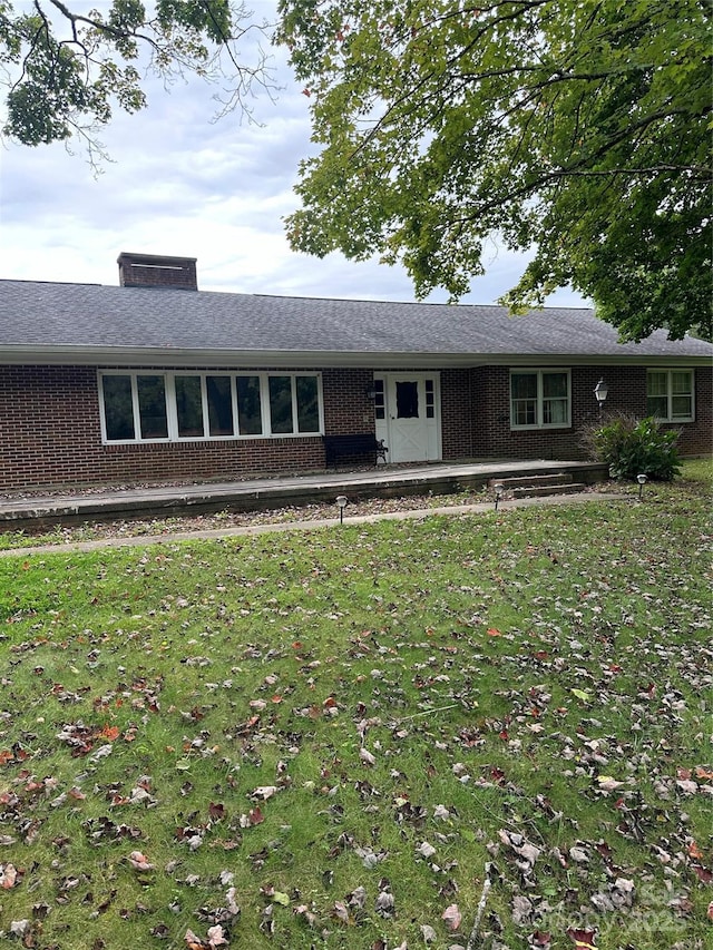 single story home with brick siding, a chimney, and a front lawn