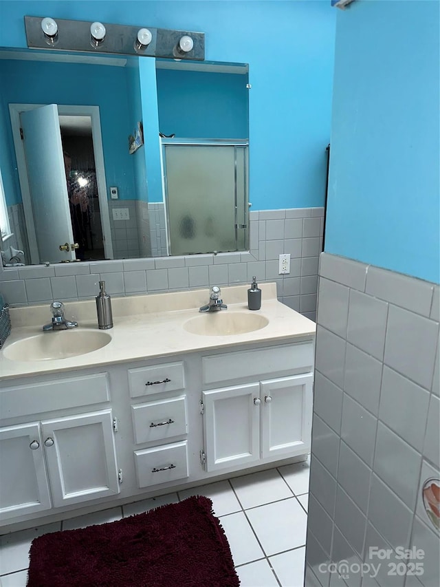 full bath with a stall shower, tile patterned flooring, a sink, and tile walls