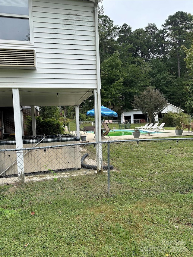 view of yard with a pool, a patio area, fence, and a wall unit AC