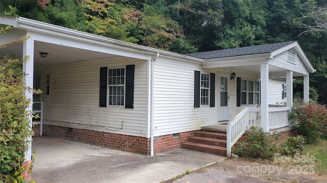 view of side of home featuring crawl space, driveway, a porch, and a carport