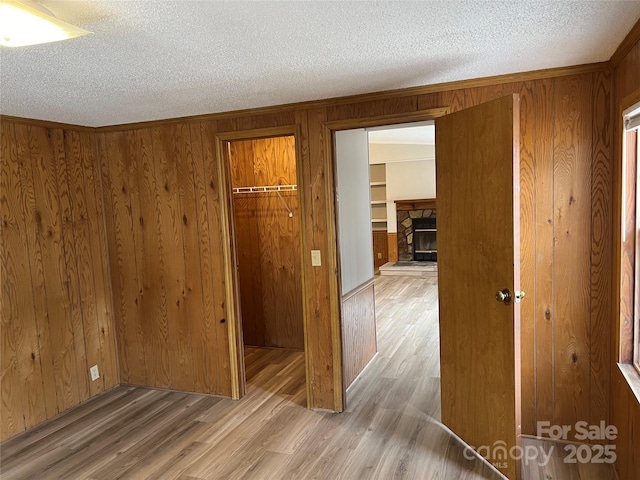 unfurnished bedroom featuring a closet, wood walls, a textured ceiling, and wood finished floors