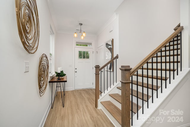 foyer entrance featuring ornamental molding, a chandelier, and light hardwood / wood-style floors