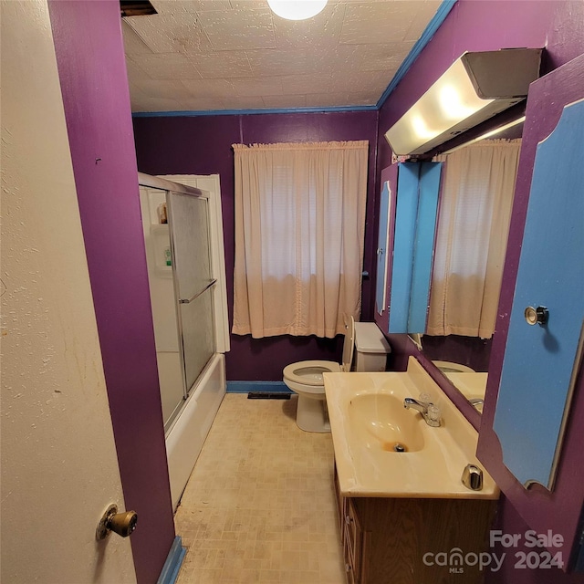 full bathroom with enclosed tub / shower combo, vanity, and toilet