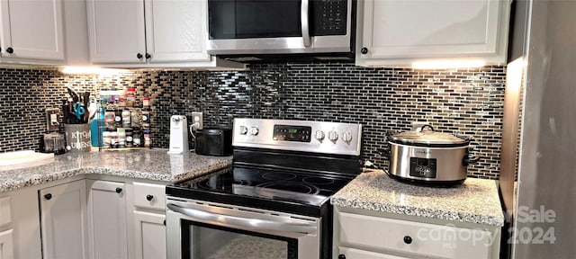 kitchen with tasteful backsplash, light stone countertops, white cabinets, and appliances with stainless steel finishes