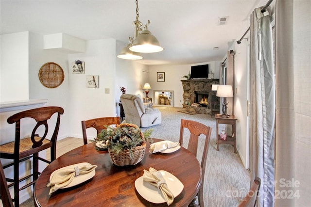 dining space with light hardwood / wood-style floors and a stone fireplace