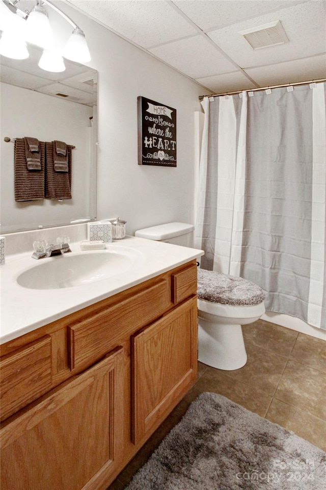 bathroom with a shower with curtain, vanity, toilet, and a drop ceiling