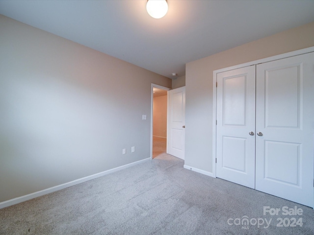 unfurnished bedroom featuring light colored carpet and a closet