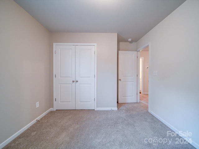 unfurnished bedroom featuring light colored carpet and a closet