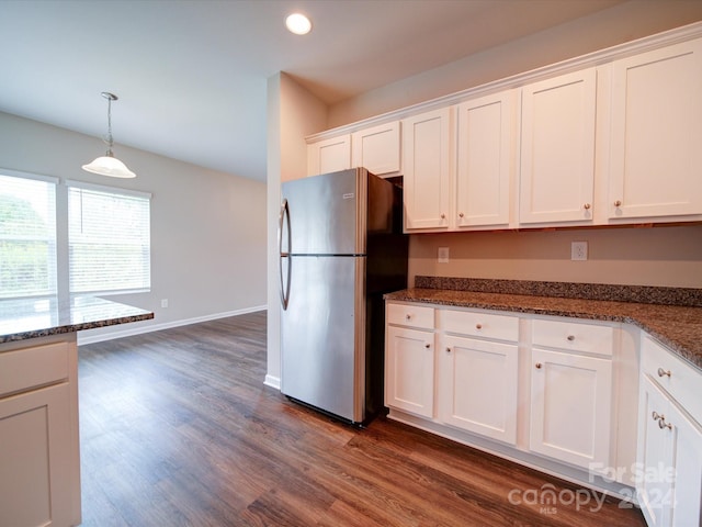 kitchen featuring dark wood-type flooring, dark stone counters, white cabinets, hanging light fixtures, and stainless steel refrigerator