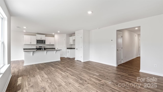 unfurnished living room featuring baseboards, wood finished floors, visible vents, and recessed lighting