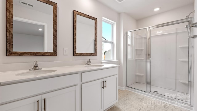 bathroom with visible vents, a sink, a shower stall, and double vanity