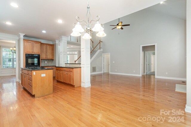 kitchen featuring light hardwood / wood-style flooring, black appliances, decorative columns, a center island, and ceiling fan with notable chandelier