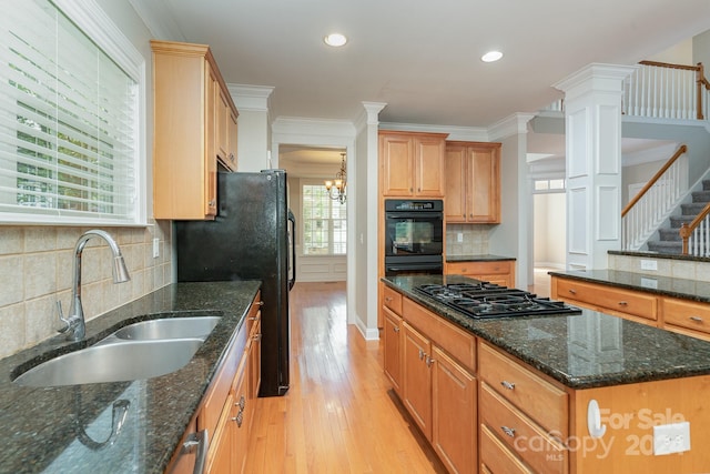 kitchen with dark stone countertops, light hardwood / wood-style floors, sink, and black appliances