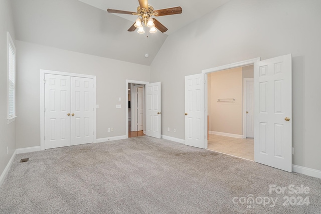 unfurnished bedroom featuring high vaulted ceiling, a closet, ceiling fan, and light colored carpet