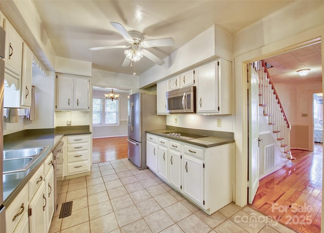 kitchen with ceiling fan with notable chandelier, visible vents, appliances with stainless steel finishes, light wood finished floors, and dark countertops