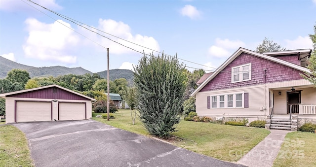 view of front of home with a mountain view, a garage, covered porch, an outdoor structure, and a front yard