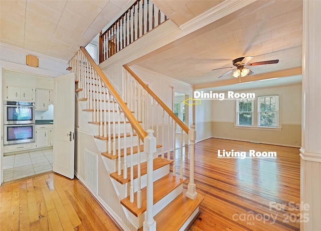 stairway with ceiling fan, crown molding, and hardwood / wood-style flooring