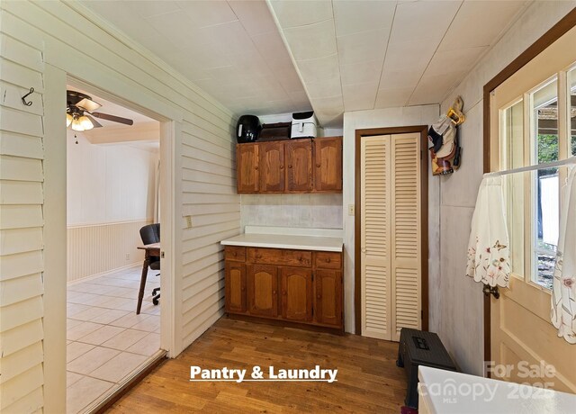 kitchen with ceiling fan, light countertops, wood finished floors, and brown cabinets