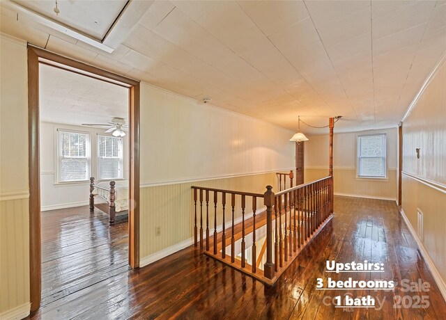 corridor featuring a wealth of natural light, wainscoting, an upstairs landing, and hardwood / wood-style flooring