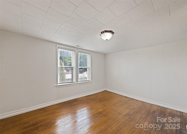 empty room with baseboards and hardwood / wood-style floors