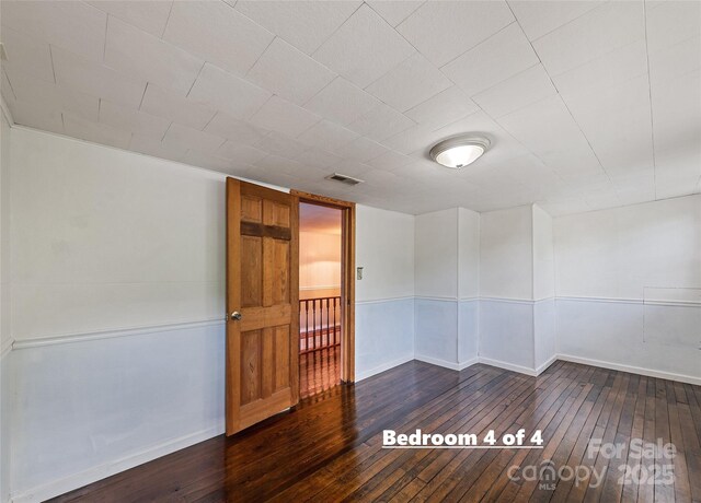 spare room featuring dark wood-style floors, baseboards, and visible vents