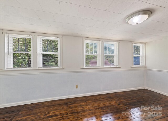 spare room featuring dark wood-style floors and baseboards