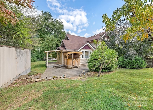 back of house featuring a patio area, a lawn, fence, and roof with shingles