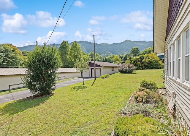 view of yard featuring a garage, a mountain view, and an outbuilding