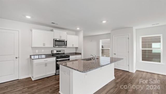 kitchen featuring dark hardwood / wood-style floors, sink, an island with sink, white cabinetry, and stainless steel appliances