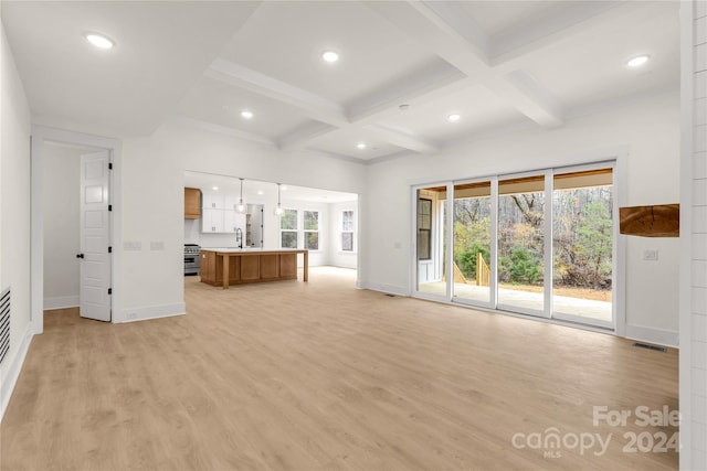 unfurnished living room with beam ceiling, light hardwood / wood-style floors, coffered ceiling, and sink