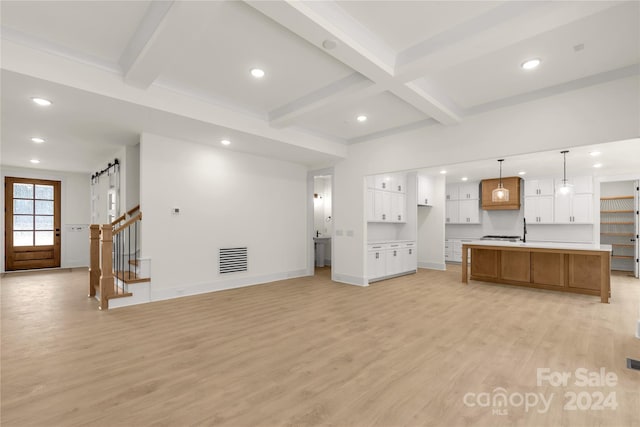 kitchen with pendant lighting, a spacious island, light wood-type flooring, beamed ceiling, and white cabinetry