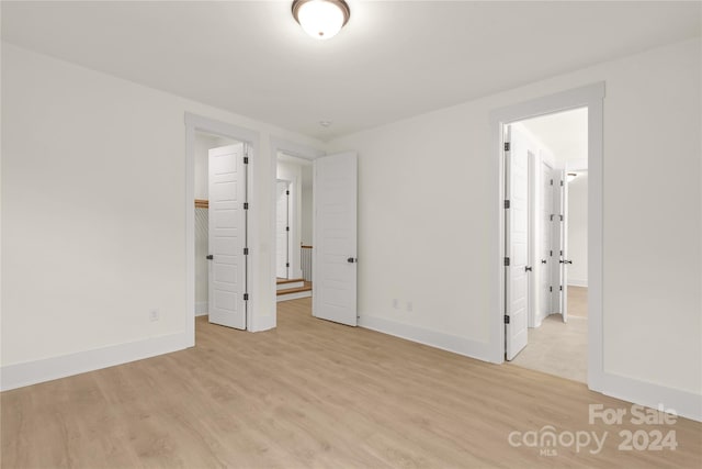 unfurnished bedroom featuring light wood-type flooring and ensuite bath