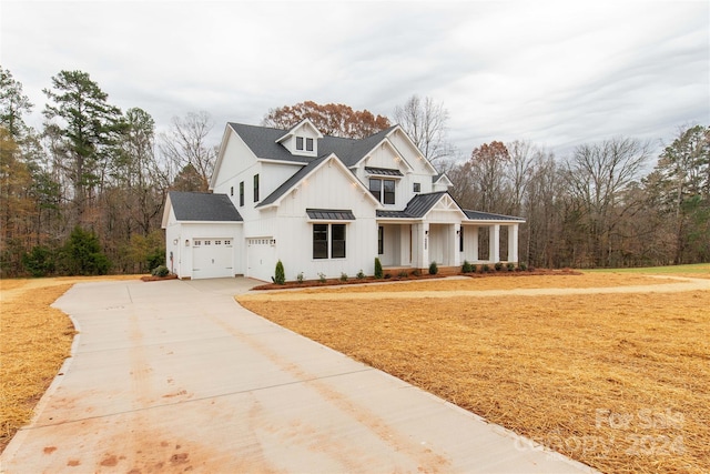 modern inspired farmhouse featuring covered porch, a garage, and a front lawn