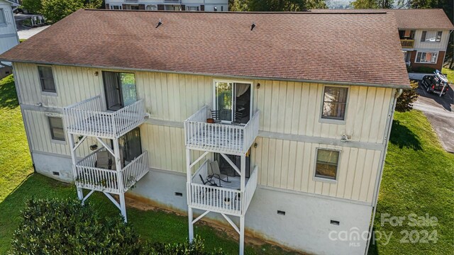 rear view of house with a yard and a balcony