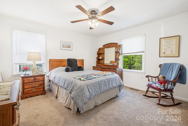 bedroom featuring light carpet, multiple windows, and ceiling fan