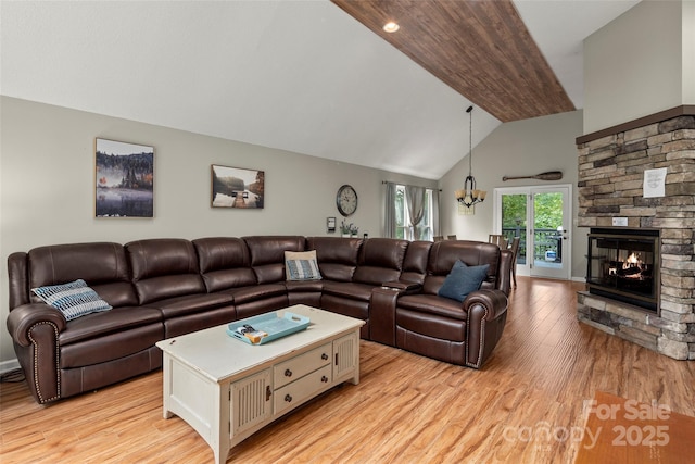 living room with high vaulted ceiling, a fireplace, a chandelier, and light hardwood / wood-style floors