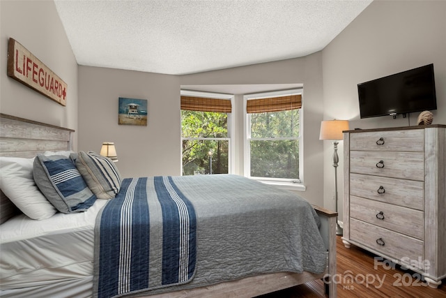 bedroom featuring vaulted ceiling, dark hardwood / wood-style floors, and a textured ceiling