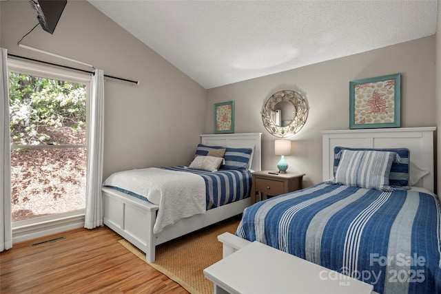 bedroom featuring vaulted ceiling, hardwood / wood-style floors, and a textured ceiling