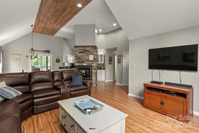 living room featuring lofted ceiling, light wood-type flooring, an inviting chandelier, and a fireplace