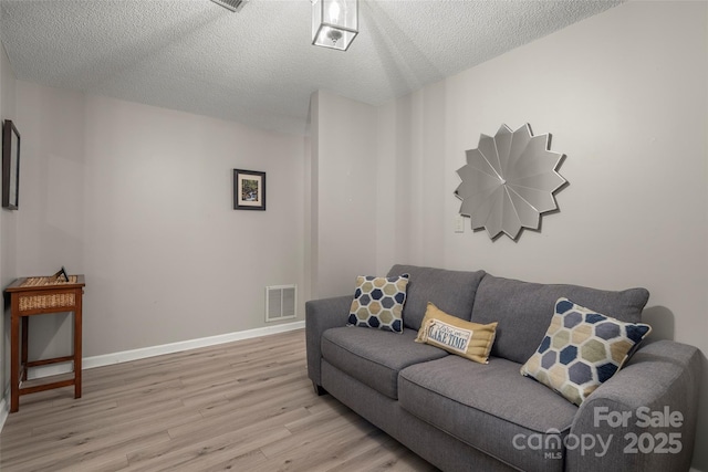 living room featuring light hardwood / wood-style floors and a textured ceiling